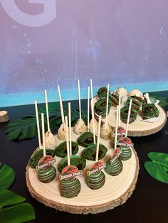 there are many desserts on the table with green leaves around them and one is made out of cake pops