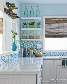 a kitchen with blue and white tiles on the walls, counter tops and shelves filled with vases