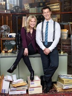 a man and woman sitting on top of stacks of books