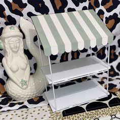 a white shelf with a green and white awning next to an elephant figurine