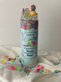 a can filled with lots of candy on top of a white blanket