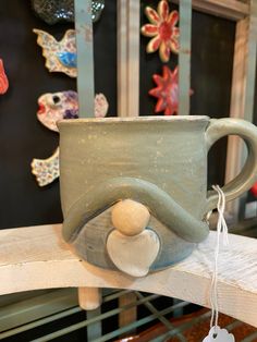 a ceramic mug sitting on top of a wooden table next to a wall with ornaments