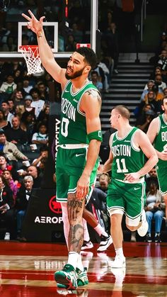 two basketball players in green uniforms are on the court