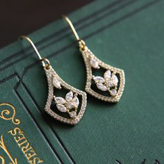 Beautiful and shiny 18k gold plated earrings in a classic 1920s style. With cubic zirconia faceted stones and finished with 18k gold plated ear hooks. The earring drops measure 2cm (0.8") in length. Perfect for any special occasion or to give as a thoughtful gift. Your earrings will arrive to you in a gift box ready to give or to treat yourself. We think these earrings are perfect for a 1920's styled wedding. If you would like a larger quantity, please DM us or email us at theprettyditty [!at] g Classic Gold Diamond Drop Earrings, Classic Yellow Gold Chandelier Earrings, Gold Cubic Zirconia Chandelier Earrings With Elegant Design, Formal Gold Diamond Teardrop Earrings, Classic Gold Diamond Earrings With Elegant Design, Classic Gold Crystal Dangle Earrings, Gold Diamond Chandelier Earrings With Elegant Design, Classic Gold Drop Chandelier Earrings, Classic Gold Diamond Earrings For Party