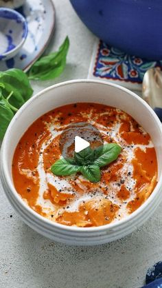 a bowl of tomato soup with basil leaves on top