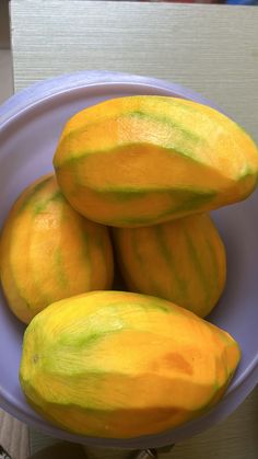 there are four melons in the bowl on the table