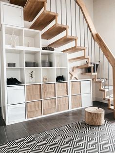 a white bookcase with drawers under a stair case next to a wooden handrail