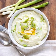 a white bowl filled with mashed potatoes and celery on top of a wooden table