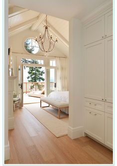 a bedroom with white walls and wood flooring has a chandelier hanging from the ceiling