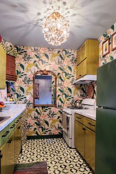 a kitchen with yellow cabinets and green appliances in the center is decorated with floral wallpaper