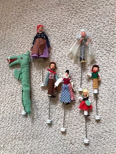 several dolls are lined up on the floor with clothes pins attached to them and one doll is wearing a red hat