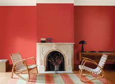 a living room with two chairs and a fire place in the center, painted bright red