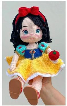 a crocheted doll in a yellow dress holding an apple