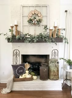 a fireplace decorated with greenery, candles and other items for the fall mantel