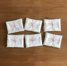 four pieces of white paper with pink bows on them sitting on a wooden table next to each other