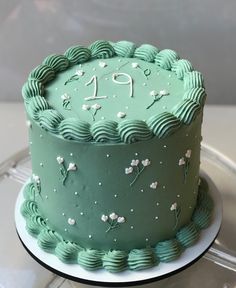 a green cake sitting on top of a glass plate covered in frosting and icing