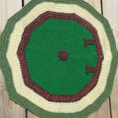 a crocheted green and white rug on top of a wooden floor