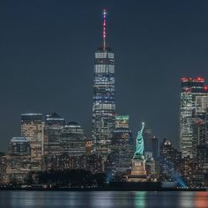 the statue of liberty is lit up in red, white and blue for the new york city skyline