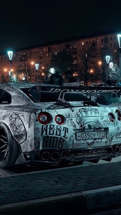 a car covered in graffiti parked on the side of a road next to street lights