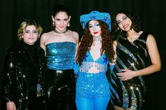 three women dressed up in costumes posing for the camera with one woman wearing blue makeup