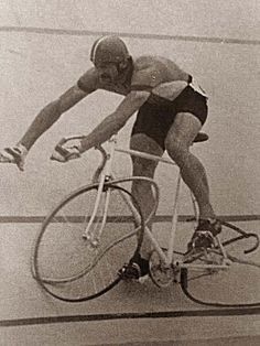 an old photo of a man riding a bike with a helmet and goggles on