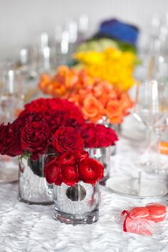 a vase filled with purple and white flowers sitting on top of a table next to wine glasses