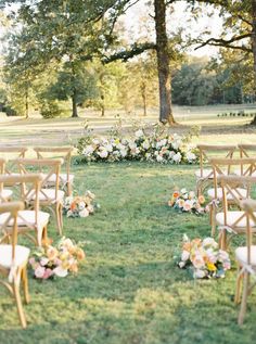 an outdoor ceremony set up in the grass with chairs and flowers on each chair for seating