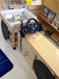 a child's playroom with toys and books on the shelves, including a steering wheel