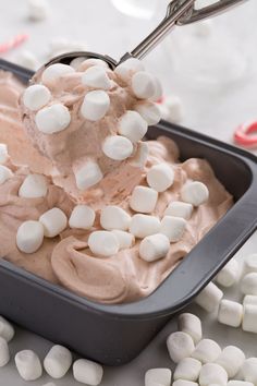 a spoon scooping marshmallows out of a pan filled with ice cream