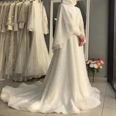 a woman standing in front of a rack of wedding gowns and looking at her dress