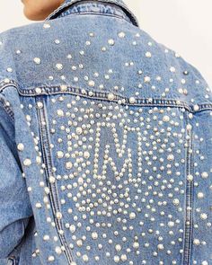 the back of a woman's jean jacket with pearls on it