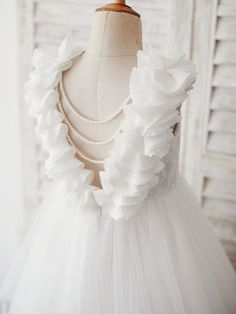 a white dress with ruffles and pearls on it