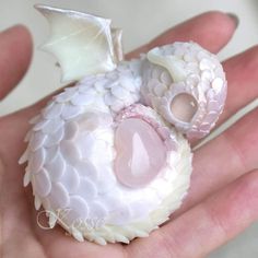 a white dragon figurine sitting in someone's hand