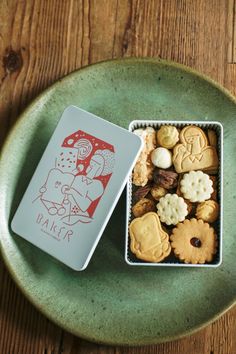 a green plate topped with cookies and crackers on top of a wooden table next to a card