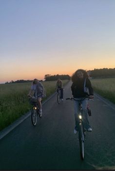 three people riding bikes down the road at sunset or dawn with one person on bike