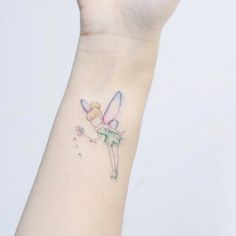 a woman's wrist with a small tattoo of a fairy on the back of her arm