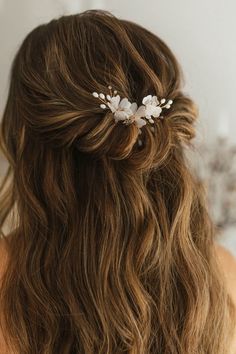 a woman with long brown hair wearing a white flower comb