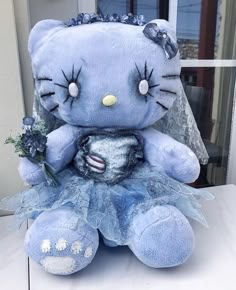 a blue hello kitty stuffed animal sitting on top of a white table next to a window