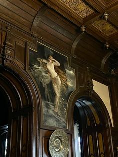 an ornate painting on the side of a wooden door in a room with wood paneling