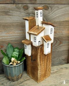 a small wooden house sitting next to a potted plant on a wood table top