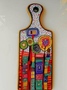 a colorful wooden cutting board hanging on the wall