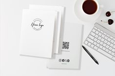 a white desk with a keyboard, mouse and cup of coffee next to some papers