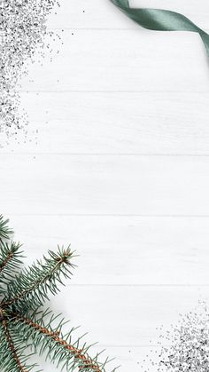 a christmas tree branch with a green ribbon on it and snow flakes around the branches