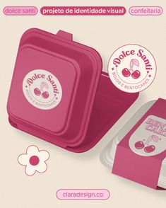 a pink lunch box with the lid open and stickers on it, next to a flower