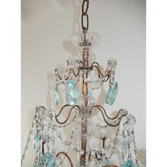 a chandelier hanging from the ceiling with blue glass beads and chains around it