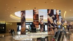 an escalator in a shopping mall with multiple pictures on the wall