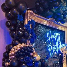 black and gold balloons are hanging from the ceiling in front of a happy birthday sign