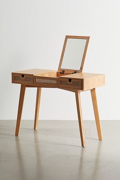 a wooden desk with a mirror on top of it and drawers underneath the table, in front of a white wall