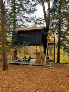 a small cabin in the woods with stairs leading up to it's roof and deck