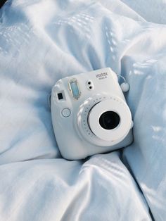 a white camera sitting on top of a bed